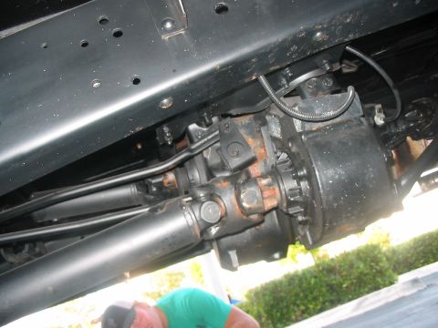 1986 Ford Bronco - Close-up view of the undercarriage of a vehicle, focusing on the transfer case and driveshaft assembly.