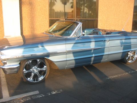 1986 Ford Bronco - Side view of a light blue 1964 Ford Galaxie convertible with custom chrome wheels.