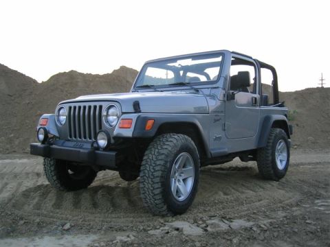 2000 Jeep Wrangler - This 2000 Jeep Wrangler is shown in a three-quarter front view, parked on a dirt lot with hills in the background.