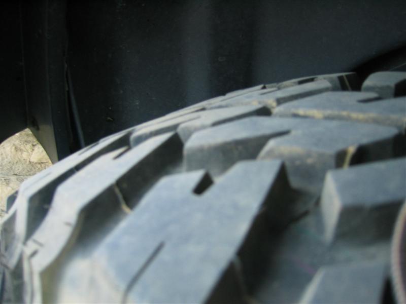 Close-up of a mud-terrain tire's blocky tread lugs inside a fender well