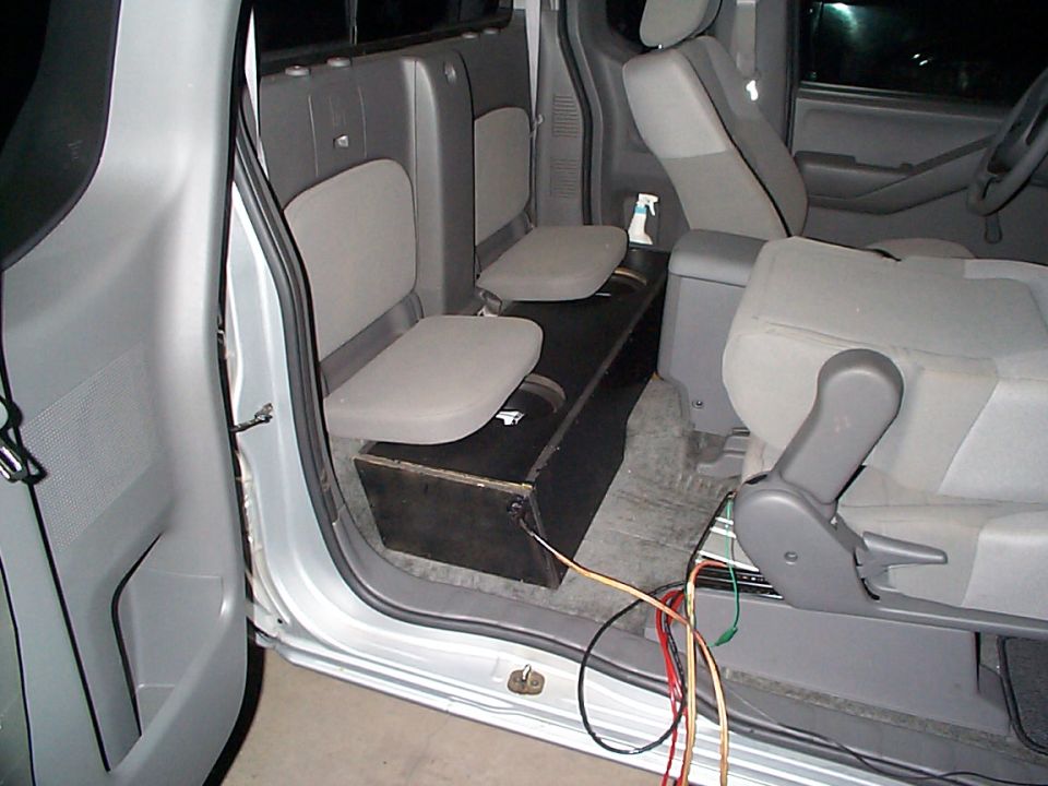 Silver 2005 Nissan Frontier interior showing the rear seats, a custom subwoofer box, and wiring