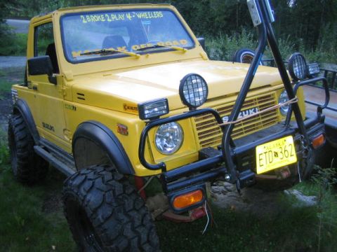 1987 Suzuki Samurai - This yellow off-road vehicle features oversized tires and a prominent aftermarket bumper.