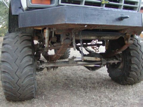 1995 Ford Bronco - The front suspension and oversized tires of a modified Ford Bronco are visible, suggesting an older model year.