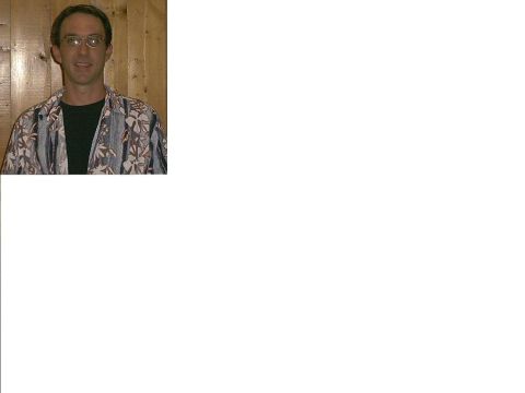 1990 Ford Bronco - A man wearing a floral print shirt and glasses stands against a wood-paneled background.