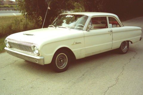 1962 Ford Falcon - A white two-door Ford Falcon is parked on a cracked asphalt surface.