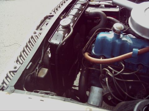 1962 Ford Falcon - Close-up view of an engine bay, blue valve covers and a radiator. The image includes a watermark for Supermotors.net.