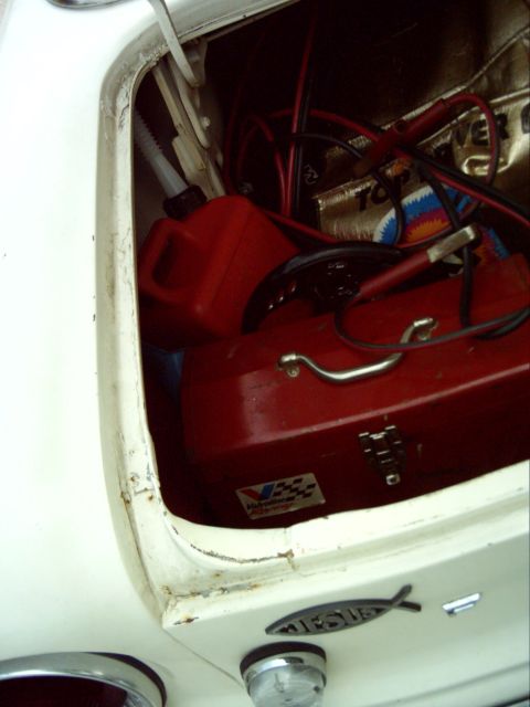1962 Ford Falcon - The trunk of a 1962 Ford Falcon contains a red toolbox, a red gas can, and jumper cables.