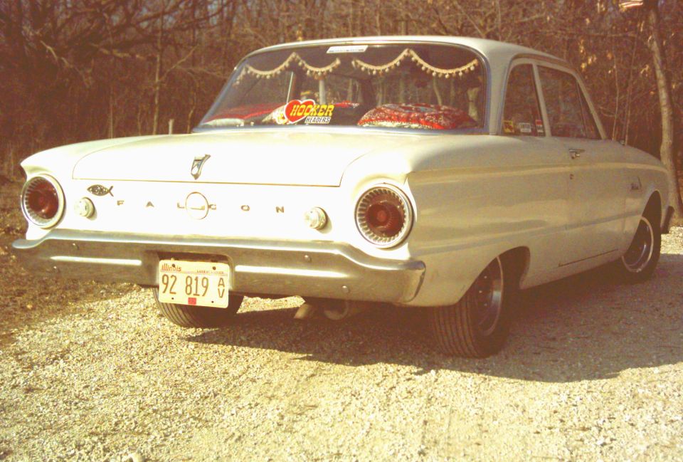 White 1962 Ford Falcon sedan, rear view, parked on gravel