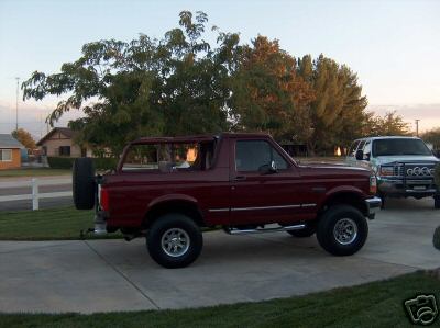 1996 Ford Bronco - A maroon Ford Bronco is parked on a driveway with a white truck in the background.