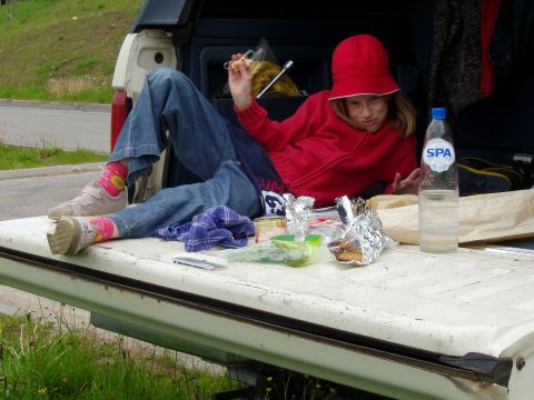 1988 Ford Bronco - A person relaxes in the back of a pickup truck, enjoying a snack and a drink.