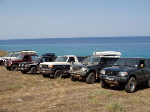 1988 Ford Bronco - A group of SUVs are parked on a hill overlooking the sea.