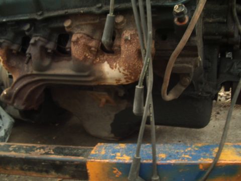 1978 Ford Bronco - Close-up view of a rusty engine component with spark plug wires attached.