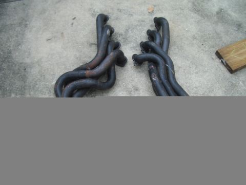 1978 Ford Bronco - Pair of exhaust headers, likely for a V8 engine, resting on concrete.