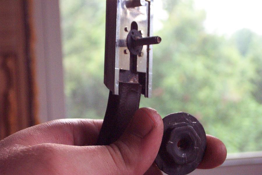 Hand holding a dark car part with a metal component attached
