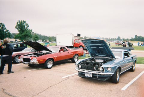 1972 Ford Ranchero - A red pickup truck with its hood open is parked at an outdoor car show.