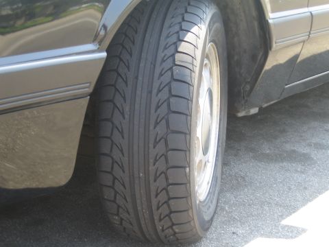 1985 Ford Mustang - A close-up view of a car's tire and fender shows the tread pattern and body trim.