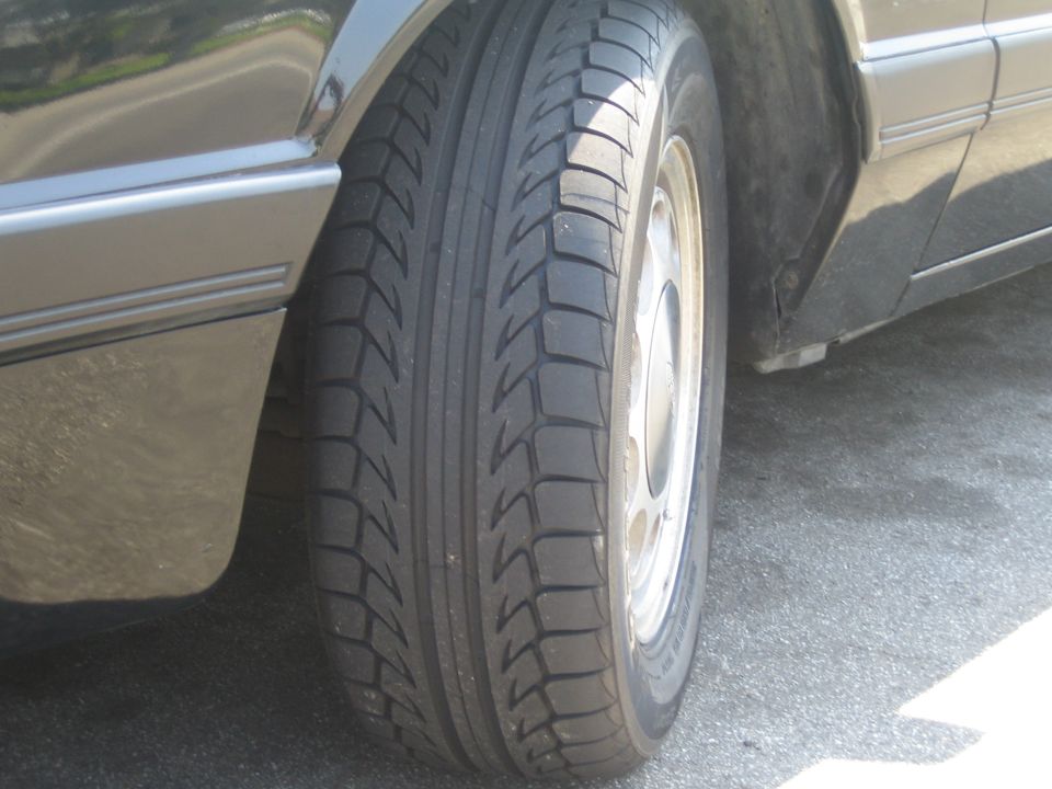 Close-up of front tire tread and silver alloy wheel on a tan car