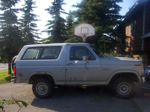 1985 Ford Bronco - This Ford Bronco is parked on a gravel driveway next to a house with pine trees in the background.