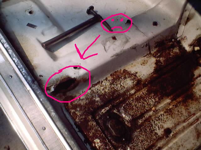 Rusty metal panel with hole circled in pink marker and annotated sad face