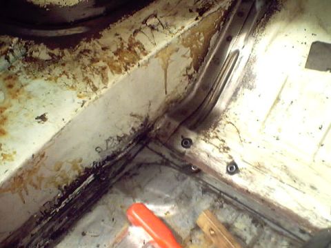 1966 Ford Fairlane - Close-up view of the interior floor pan and structural supports, showing signs of rust and debris before restoration.