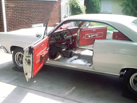 1966 Ford Fairlane - The interior of a 1966 Ford Fairlane is shown with both front and rear doors open, revealing the red door panels and the floor stripped for…