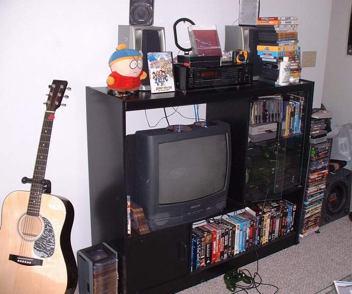 This is our living room entertainment center. We have XBox, Nintendo, a DVD/VCR combo, and tons of DVDs and videos. There's a 4-channel speaker system hooked up as well. The sub is mine so it ended up in my room with my little 15" tv. The plush Cartman is mine, too. Every bachelor pad needs that. The guitar is my brother's.
