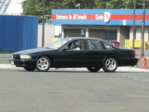 2001 Mercury Grand Marquis - A black sedan with racing numbers '270 E' on the door is seen from the side, with a driver wearing a helmet inside.