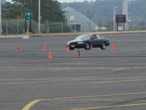 2001 Mercury Grand Marquis - A black sedan is shown navigating a course marked by orange traffic cones in an open paved area.