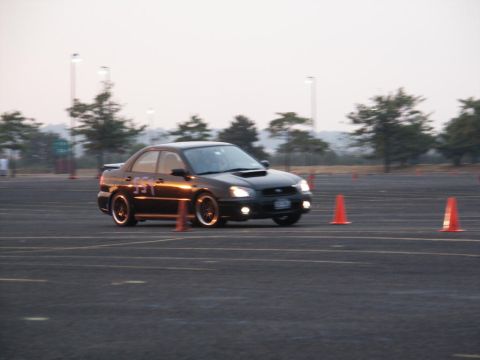 2001 Mercury Grand Marquis - A black Subaru Impreza WRX is seen on a track, maneuvering through orange cones during what appears to be a timed event.