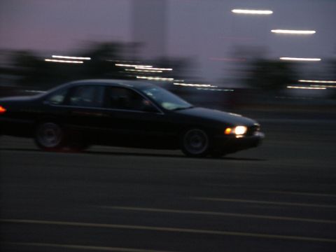 2001 Mercury Grand Marquis - A dark sedan is captured in motion at dusk, with streaks of light in the sky and on the road.