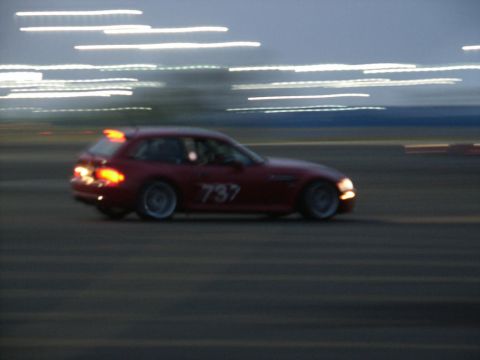 2001 Mercury Grand Marquis - A red station wagon with the number 737 is captured in motion on a track as daylight fades.