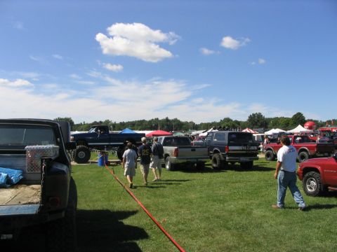 1986 Ford Bronco - A sunny day at a vehicle show with many trucks and SUVs on display.