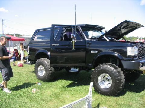 1986 Ford Bronco - This lifted Ford Bronco is on display at an outdoor event with its hood open.