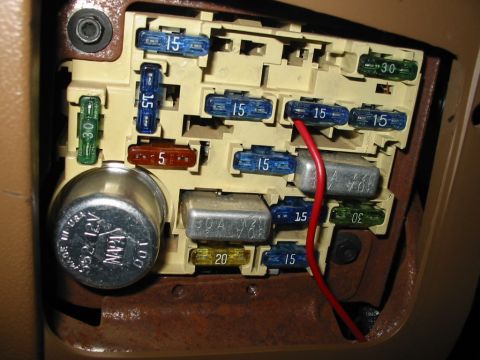 1988 Ford Bronco - Close-up of a vehicle's interior fuse box, showing multiple fuses and a metal component.