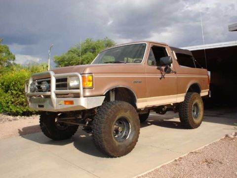 1989 Ford Bronco - This lifted Ford Bronco features a soft top and a prominent brush guard on the front bumper.
