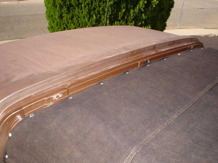 Brown car roof with visible seams and fasteners, next to a dark fabric top