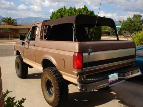 1989 Ford Bronco - This 1989 Ford Bronco features a removable soft top and aggressive off-road tires, seen from the rear.