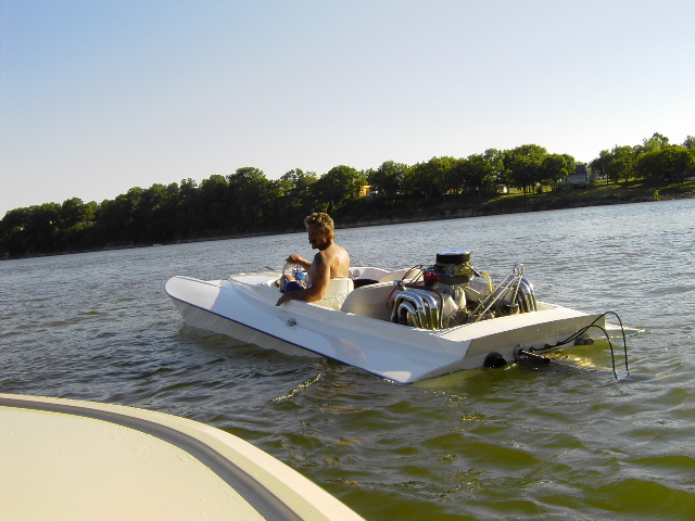 Boat with exposed engine and driver on water