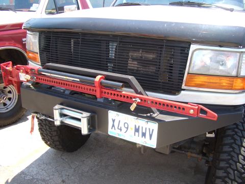 1990 Ford Bronco - 1990 Ford Bronco front view showing winch and Hi-Lift jack. Another vehicle is partially visible to the left.