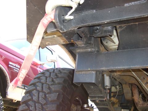 1990 Ford Bronco - A red 1990 Ford Bronco is visible with a tow strap and large off-road tire in this side view.