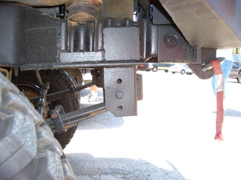 1990 Ford Bronco - The underside of a vehicle shows its suspension components and frame, with other vehicles visible in the background.