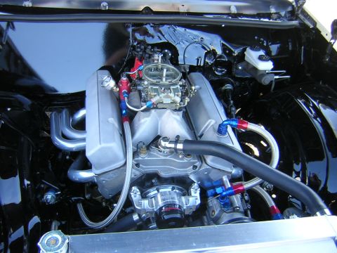 1998 Ford Crown Victoria - highly polished V8 engine topped with a dual-quad carburetor and chrome headers sits in a glossy black-painted engine bay.