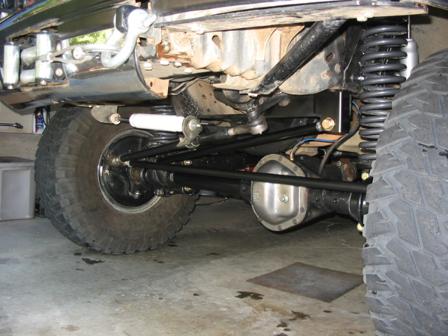Undercarriage of lifted Bronco front axle with coil springs and mud tires in garage