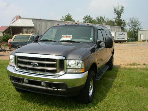 1995 Ford Bronco - Ford Excursion SUV with a 'FOR SALE' sign on the windshield. Another vehicle is parked in the background.