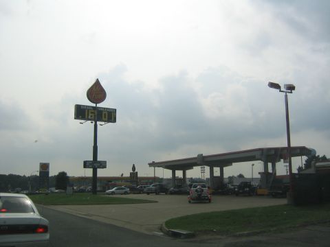 1978 Ford Bronco - A gas station scene with a prominent Mr. Fuel sign displaying fuel prices under a cloudy sky.