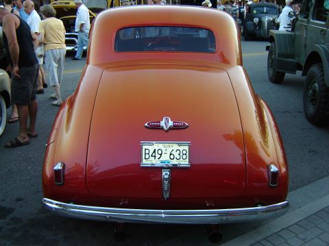 1990 Ford Thunderbird - A classic Buick coupe is parked on the street, with other vehicles and people in the background.