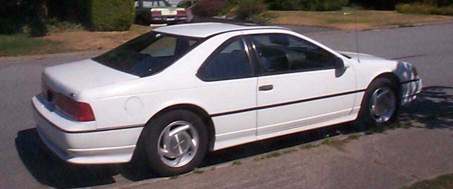 White Ford Thunderbird coupe parked curbside, rear three-quarter passenger side view