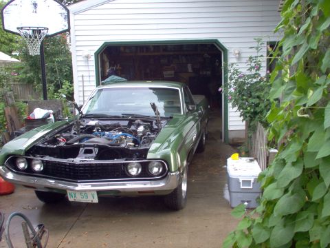 1970 Ford Ranchero - A 1970 Ford Ranchero is parked in front of an open garage with its hood up, revealing the engine.