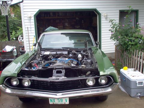 1970 Ford Ranchero - The front of a green 1970 Ford Ranchero is visible with its hood open, revealing the engine bay.