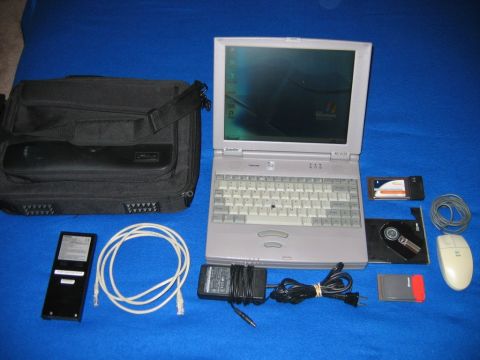 1985 Ford LTD Crown Victoria - A collection of vintage computer equipment, including a laptop, bag, and various accessories, laid out on a blue cloth.